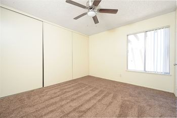 A bedroom with white walls and a ceiling fan